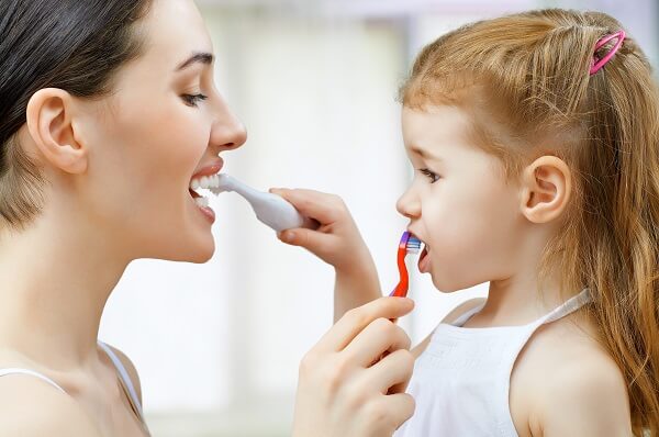 woman and child brush each other's teeth